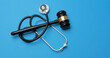 © Piya W. - Serious medical gavel and stethoscope representing ethical medicine law justice malpractice and professional healthcare on blue background