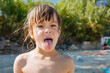 © Victoria - Playful Young Girl Sticking Out Tongue at Beach During Summer Vacation