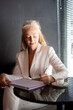 © Cavan - Thoughtful mature businesswoman with coffee and notebook