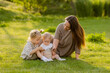 © Tina kids photo - mother with two daughters sitting on a lawn at sunset in the summer, hugging