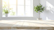 © Sikat - Bright and Airy Room with Wooden Table and Plants by the Window.