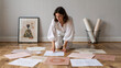 © Oleg - Artist reviewing sketches on the floor