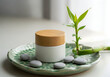 © MdEashad - Spa composition with white cosmetic jar bamboo lid on green plate with smooth stones and lucky bamboo plant.