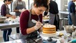© Rayn - Ambitious young woman in a bakery workshop using a piping bag. Representing youth empowerment, creative talent, and professional training in the food industry