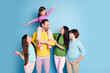 © deagreez - Happy family with parents and three children posing playfully against a blue background, father carrying youngest daughter on his shoulders while everyone smiles in casual colorful clothes