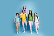© deagreez - Happy family portrait of parents and three children walking together in colorful casual clothes against a blue studio background