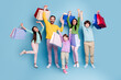 © deagreez - Happy family shopping together with colorful bags celebrating a successful day out and joyful parents and children posing against a blue background