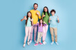 © deagreez - Happy family of five giving thumbs up together in colorful casual clothes on blue background, parents and three children smiling and showing positive support