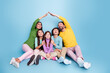 © deagreez - Happy family of five sitting together under parents' roof gesture, smiling children and parents showing love, protection and playful togetherness in a colorful studio portrait
