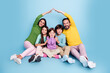 © deagreez - Happy family of five sitting together making a roof with their arms, parents and children smiling in a colorful studio portrait showing love, togetherness and home protection