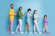 © deagreez - Happy family of five standing in a row with smartphones, parents and children smiling in colorful casual clothes against a blue background