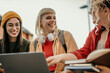 © La Famiglia - Diverse students learning together outdoors using laptop