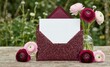 © Natalia - Burgundy Glitter Envelope with White Card and Pink Ranunculus Flowers on Wooden Table for Wedding Invitation