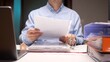 © Aliaksandr - Person reviewing important documents and contracts related to real estate investment, property management, or mortgage agreements while working at a desk with a laptop and folders