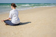 © Юлия Завалишина - Yoga calm mindfulness meditation. Young healthy woman practicing yoga on beach. Woman sitting in lotus pose meditating relaxing connection with nature by the sea. Girl doing breathing practice
