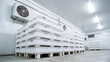 © photo for everything - Industrial Cold Storage Facility Interior with Stacks of White Plastic Crates on Pallets and Modern Refrigeration Units on Ceiling