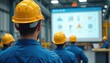 © Pete - Workers in blue overalls, yellow hard hats attend safety training in factory. Instructor presents information on large screen display. Team listens to lecture in industrial setting learning