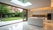 © Pete - Modern kitchen extension with garden view. Sleek white island with sink. Large sliding glass doors open to lush green lawn. Skylight ceiling lets in natural light. Contemporary luxury home.