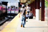 Rear view of a young boy carrying a skateboard on a train station platform in Boston during a family road trip across America.