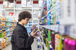 © Светлана Мищенко - Teenage boy choosing canned beverages in supermarket and reading product label. Energy drink consumption, sugar intake, caffeine habits and health awareness for adolescents concept.
