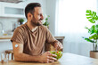 © Dragana Gordic - Man Eating Healthy Salad at Home Wearing Glucose Monitor Sensor Patch, Smiling in Kitchen