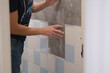 © smile35 - A man glues wall panels onto old tiles. A quick and affordable renovation