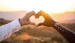 © Aken - Two hands making heart shape against a sunset mountain vista