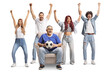 © Ljupco Smokovski - Man sitting in an armchair with a football and cheering with a group of young people