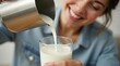 © Tsalsa - Happy young woman pouring fresh organic milk into a glass.