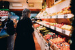 © BullRun - Middle aged woman shopping for fresh fruits in grocery store, female customer looking at local produce in market, healthy lifestyle and sustainability concept, authentic daily routine