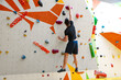 © New Africa - Athletic young man climbing wall in gym, back view. Space for text