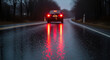 © Shakil - Black car driving away on a wet asphalt road during a gloomy evening with bright red taillights glowing in darkness