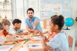© chokniti - Back to school and education concept of teacher guiding children in classroom, group drawing activity with colorful paper and crayon, diverse student learning art and education