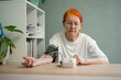 © Sk Elena - A senior lady is seated at a table, patiently waiting for the outcome of her blood pressure measurement on the tonometer. This daily checkup is crucial for managing health