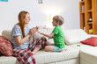 © KONSTANTIN SHISHKIN - Mother and child play clapping game at home during daytime in cozy living room setting