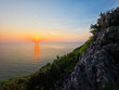 © CoreRock - Peaceful sunset over ocean horizon viewed from steep rocky cliff with lush green vegetation evoking serene and calm tranquil feeling in majestic beautiful nature environment setting
