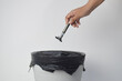 © Maule - A close-up view of a woman's hand releasing a used manual razor into a white trash can with a black bag, set against a clean white background