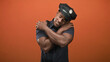 © Krakenimages.com - Man police officer wearing cap and badge with bare muscular arms hugging shoulders and smiling in studio; self care contentment.