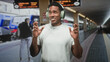 © Krakenimages.com - Man with green overear headphones and white tshirt smiling and gesturing with hands on a train platform inside a building; joyful escape.