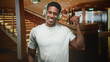 © Krakenimages.com - Man with headphones smiling and thumb up gesture in hotel lobby pointing toward staircase and chandelier, wearing white tshirt; relaxed joy.