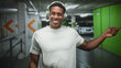 © Krakenimages.com - Man wearing headphones and white t shirt pointing right with finger toward a parked car inside a parking building; joyful listening groove.