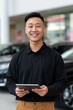 © Andrii Zastrozhnov - Young man smiling holding tablet inside car showroom