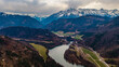 © AmazingAerialAgency - Klaus an der Pyhrnbahn, Austria - 23 March 2026: Aerial view of the VOEST Quarry and the winding river valley surrounded by forested hills and snow-capped Alpine peaks under a cloudy sky.