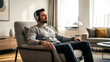 © v.stock - A smiling young man and a relaxed businessman sitting on a sofa at home using a phone and laptop for casual lifestyle and business.