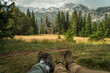 © olezzo - Panoramic view of high mountains with blurred legs of hikers in the foreground sitting on a green meadow, selective focus.