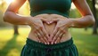 © Maryna - Asian woman forms heart shape over stomach outdoors. Female shows body love and acceptance with hands over abdomen. Healthy lifestyle, fitness and wellness theme.