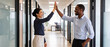 © tinybrushcreations - diverse professionals high-fiving in modern office corridor with natural lighting