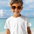 © Vitalii - Smiling child in white t shirt mockup and colorful sunglasses by the sea. Beach holiday setting for apparel design presentation