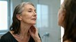 © Frame of the Dark - Beautiful mature woman looking in mirror for skin care routine, healthy aging and wellness concept