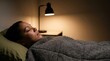 © Николай Срибяник - African American woman sleeping peacefully in bed with bedside lamp light.